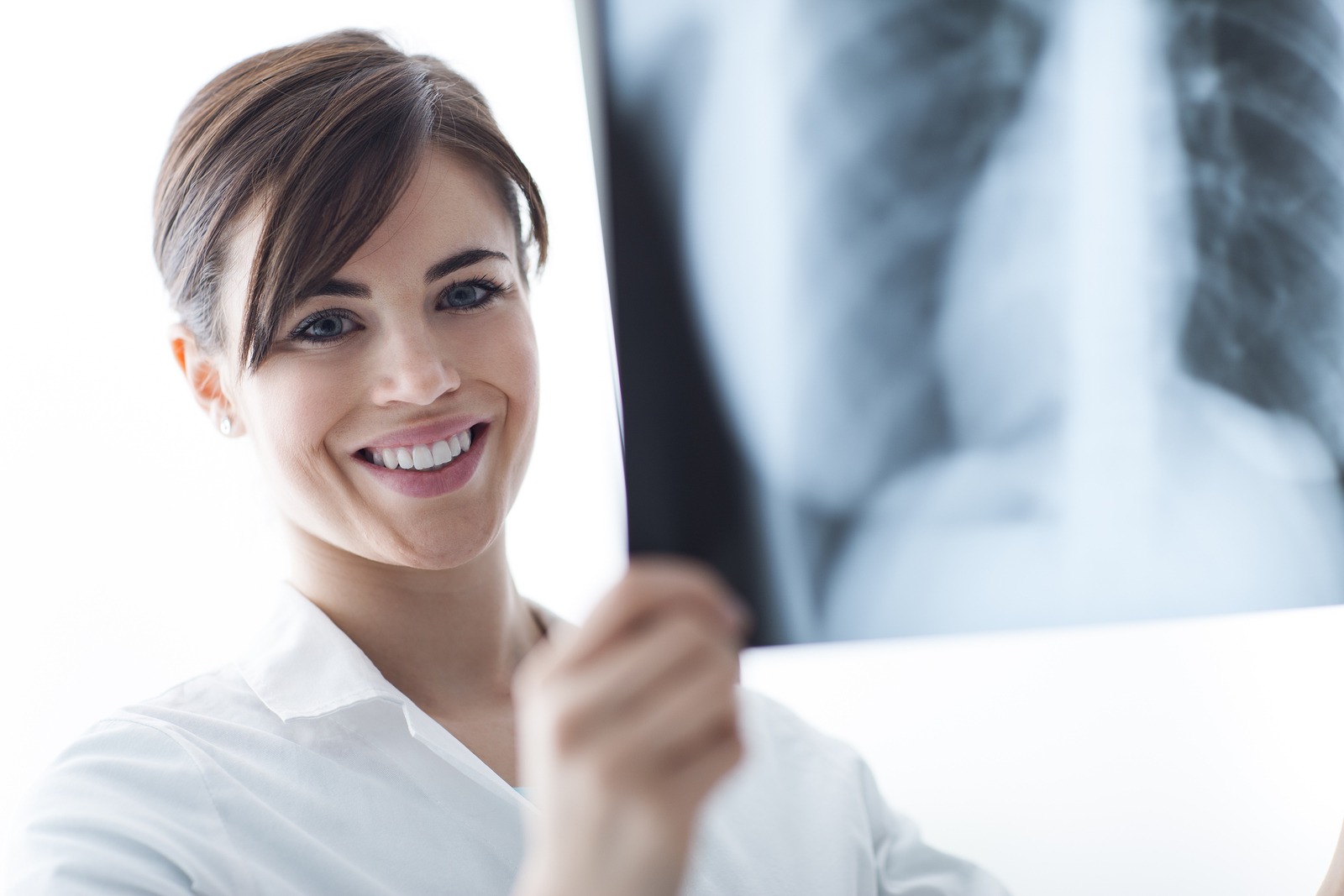  A female doctor in a white coat is looking at an x-ray of a patient's lungs.